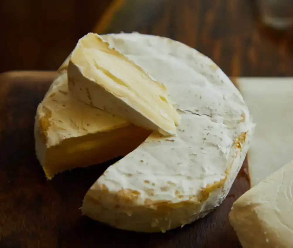 Aged cheese wheel resting on wooden board