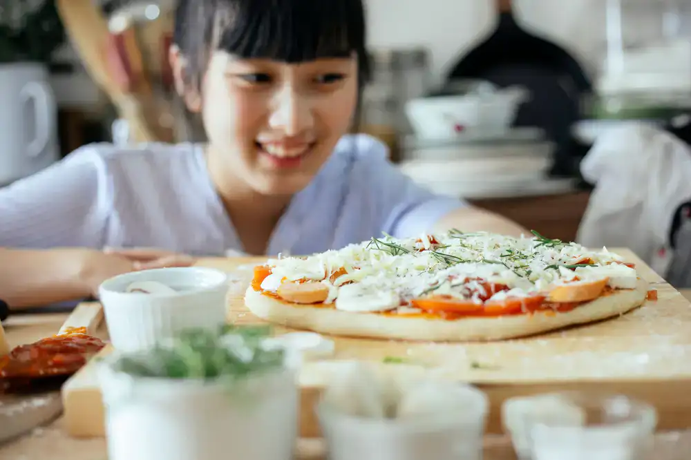 A beginner student smiling while stretching fresh mozzarella